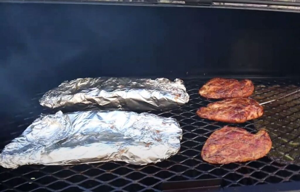 Wrapped ribs and chicken placed in the smoker