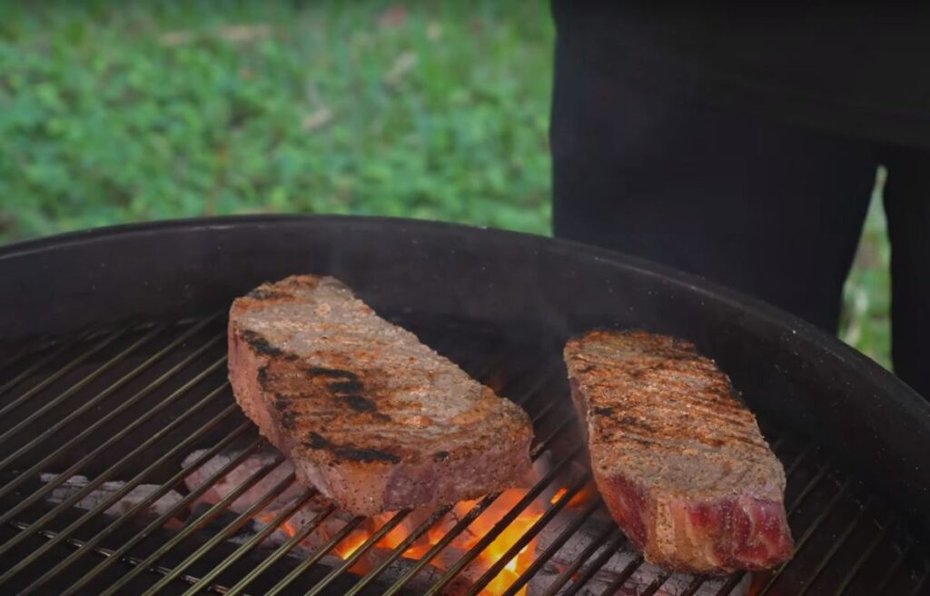 Searing two ribeye steaks on hot side of the grill